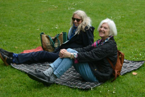 Two women sitting on a picnic blanket smiling 