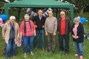 A group of people standing in front of a green marquee 