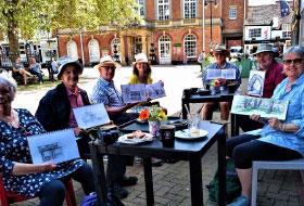 group of people at a cafe holding up their sketches