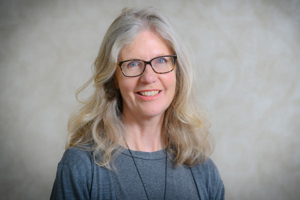 A blonde woman standing against a grey background
