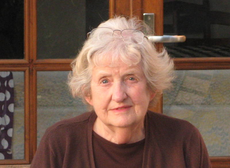 Woman with white hair in brown cardigan and top