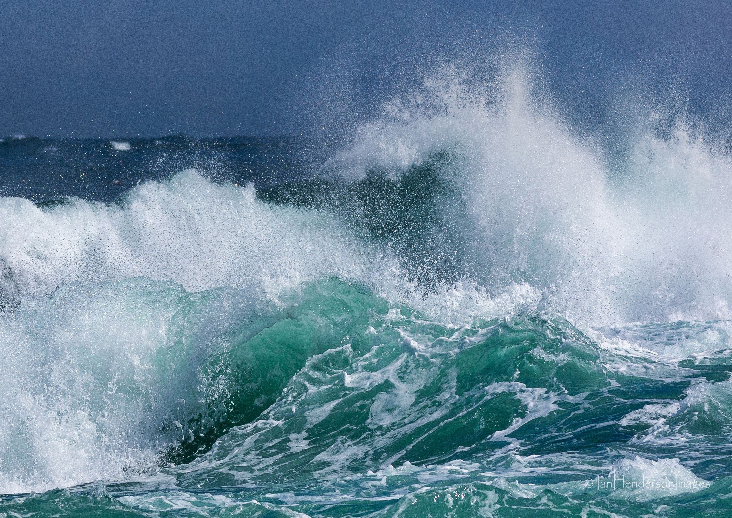 waves crashign in the sea with blue sky behind