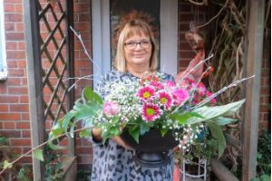 A woman smiling at the camera and holding a bouquet of flowers