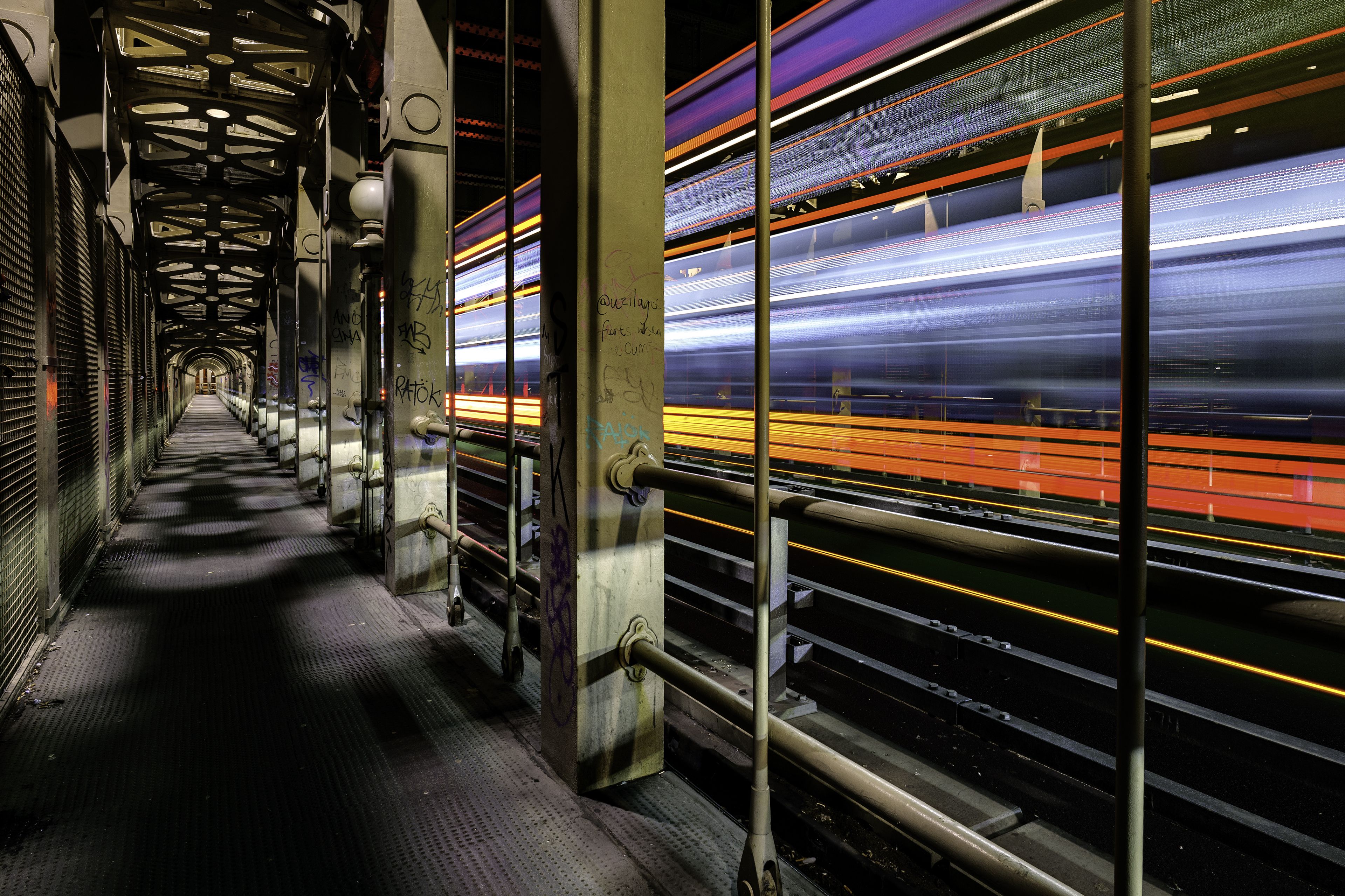 A photo from the inside of a bridge that you can walk in. A train goes by quickly, which is blurred because of the movement. 