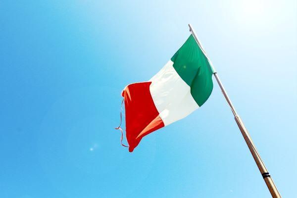 italian flag flying in the breeze against blue background on brown pole