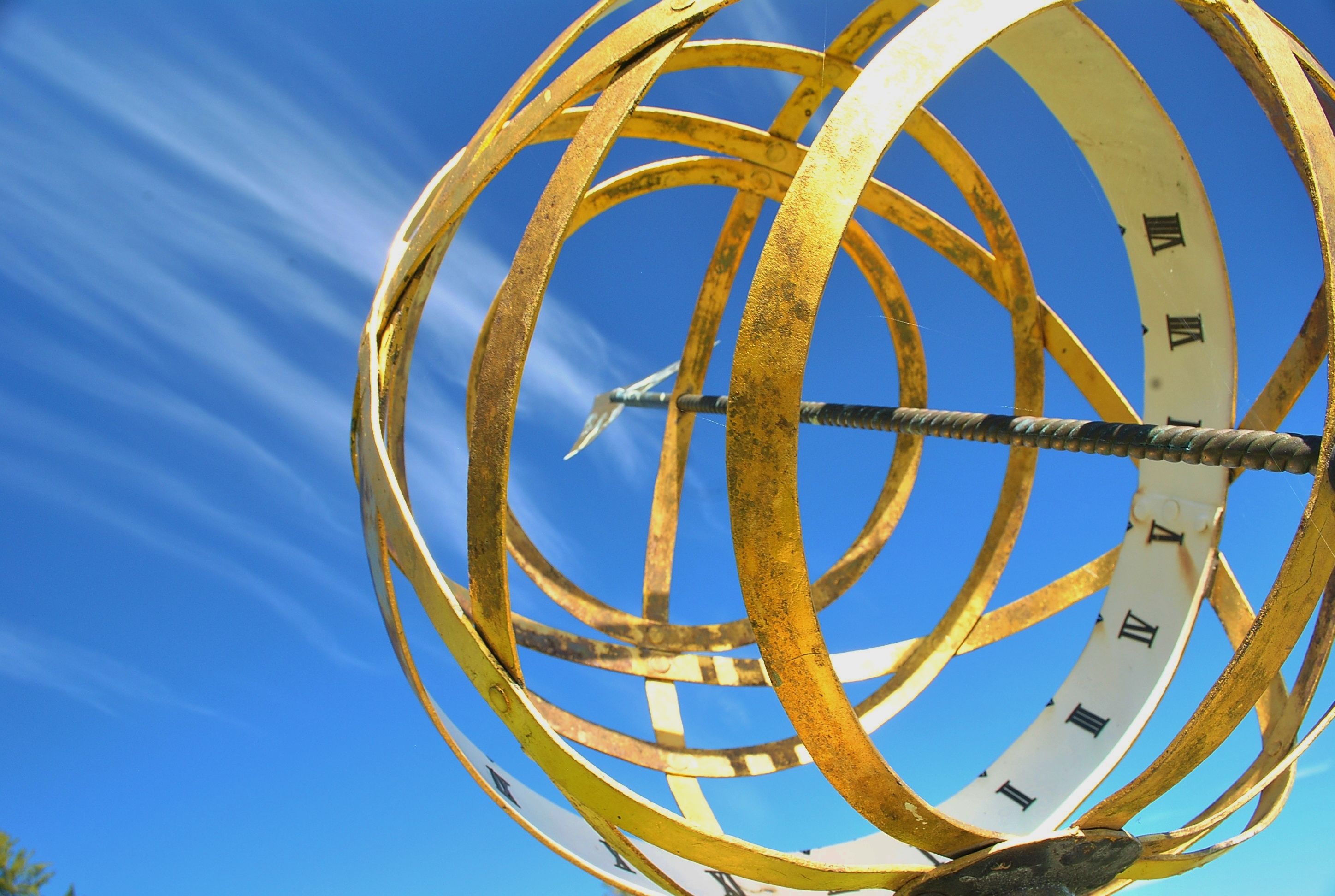 metal gold circles arranged in a spherical format, looking striking against a bright blue sky