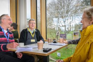 u3a members sitting around a table chatting and laughing at the u3a off the wall event