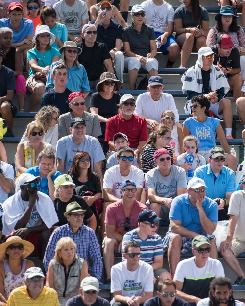 a crowd of people watching tennis in the sunshine
