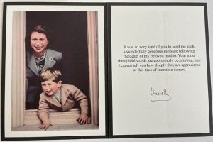 A photograph of a card. On one side is a picture of a young woman (Queen Elizabeth II) with a young blonde boy (King Charles III.) On the right hand side of the card is a typed message which reads, 'It was so very kind of you to send me such a wonderfully generous message following the death of my beloved mother. Your most thoughtful words are enormously comforting, and I cannot tell you how deeply they are appreciated at this time of immense sorrow." Below is a signature that reads, CharlesR