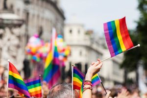 A view of a Pride march - many hands are holding up Pride flags.