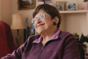 A woman in a purple jumper is smiling at the camera