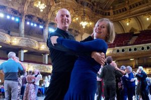 A man and woman dancing in a full ballroom