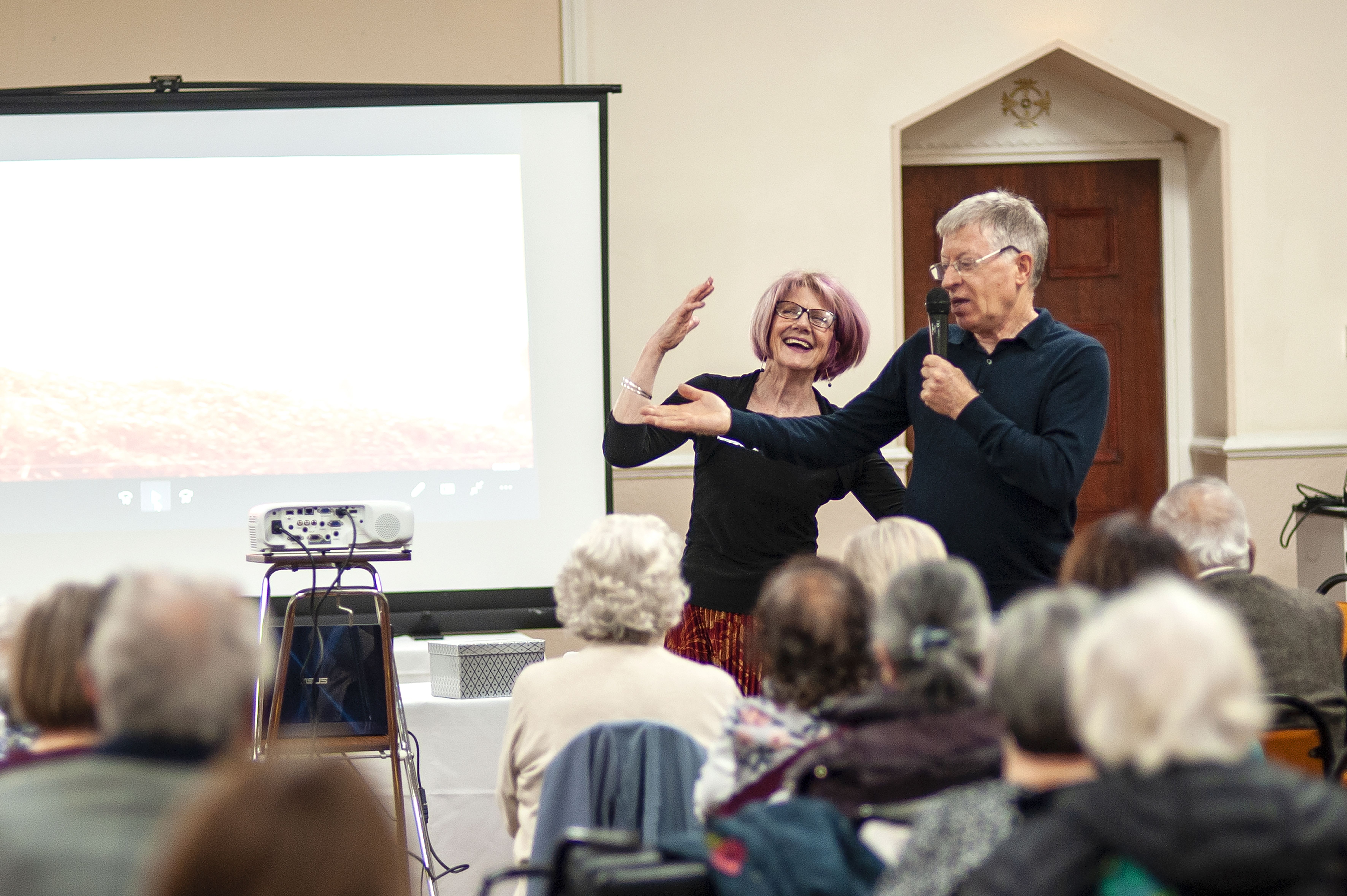 u3a members laugh while presenting with a projector at a meeting