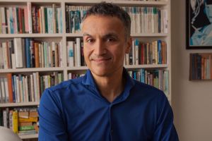 A man (Carl Honoré) sitting in front of a bookcase