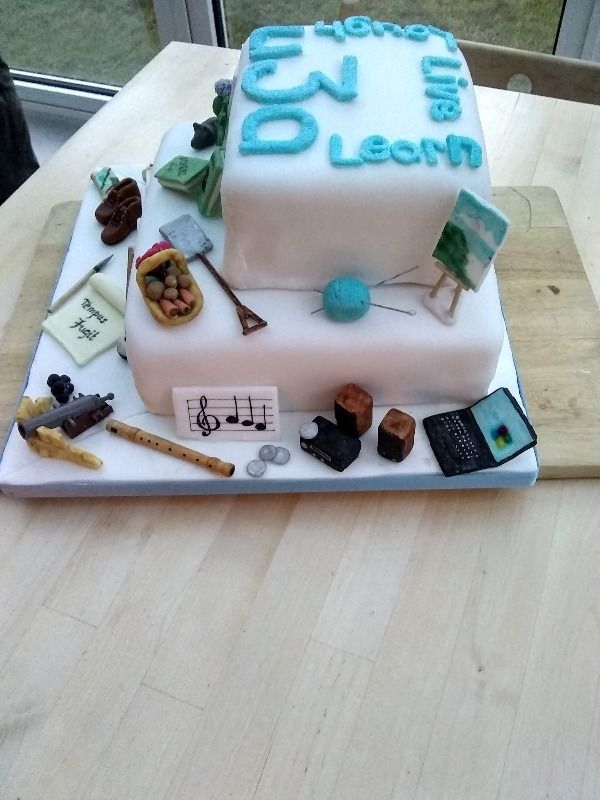 other sideview of decorated two tier cake with u3a activities depicted in icing 