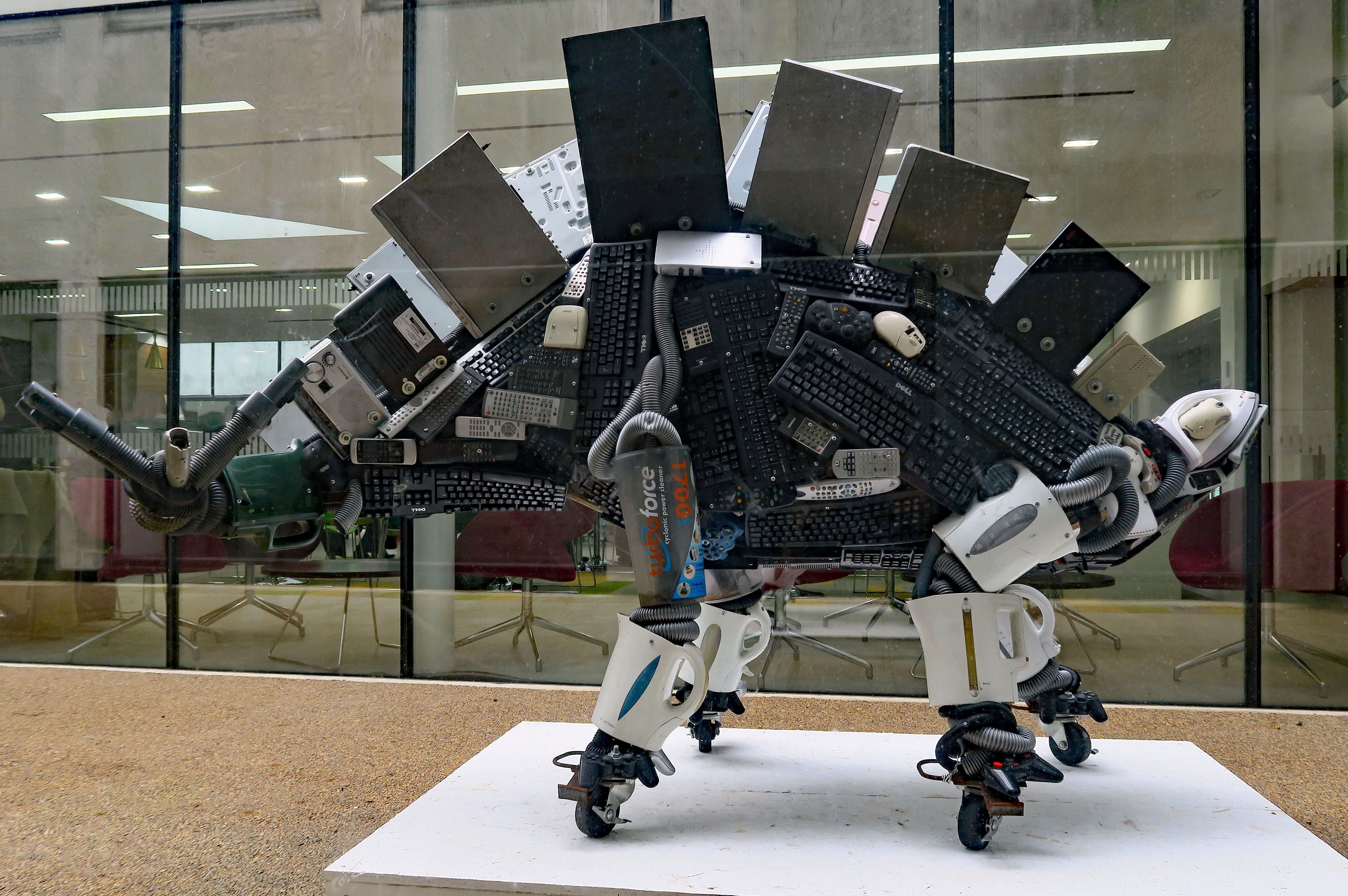 a dinosaur made out of keyboards, kettles and other small electrical appliances 