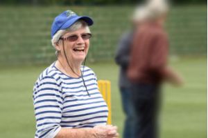 Women smiling at camera in front of a cricket ground