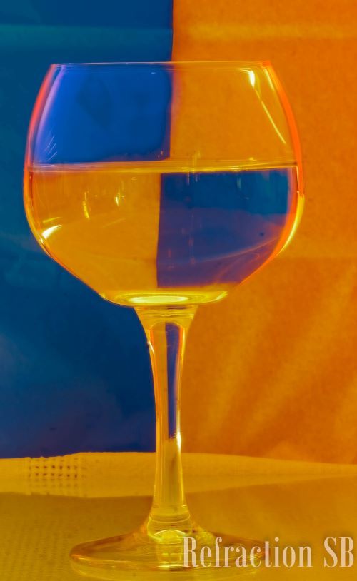a gin glass of water with a yellow and blue flag behind it to create a pattern