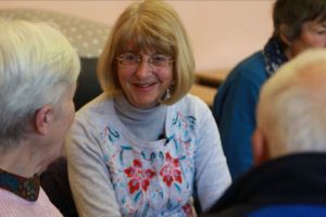 A blonde woman sitting in a group smiling