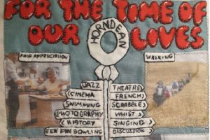 A grey quilt block with the words 'For the time of our lives' at the top. It also has a sign post with names of groups and two pictures showing a food appreciation group and a walking group.