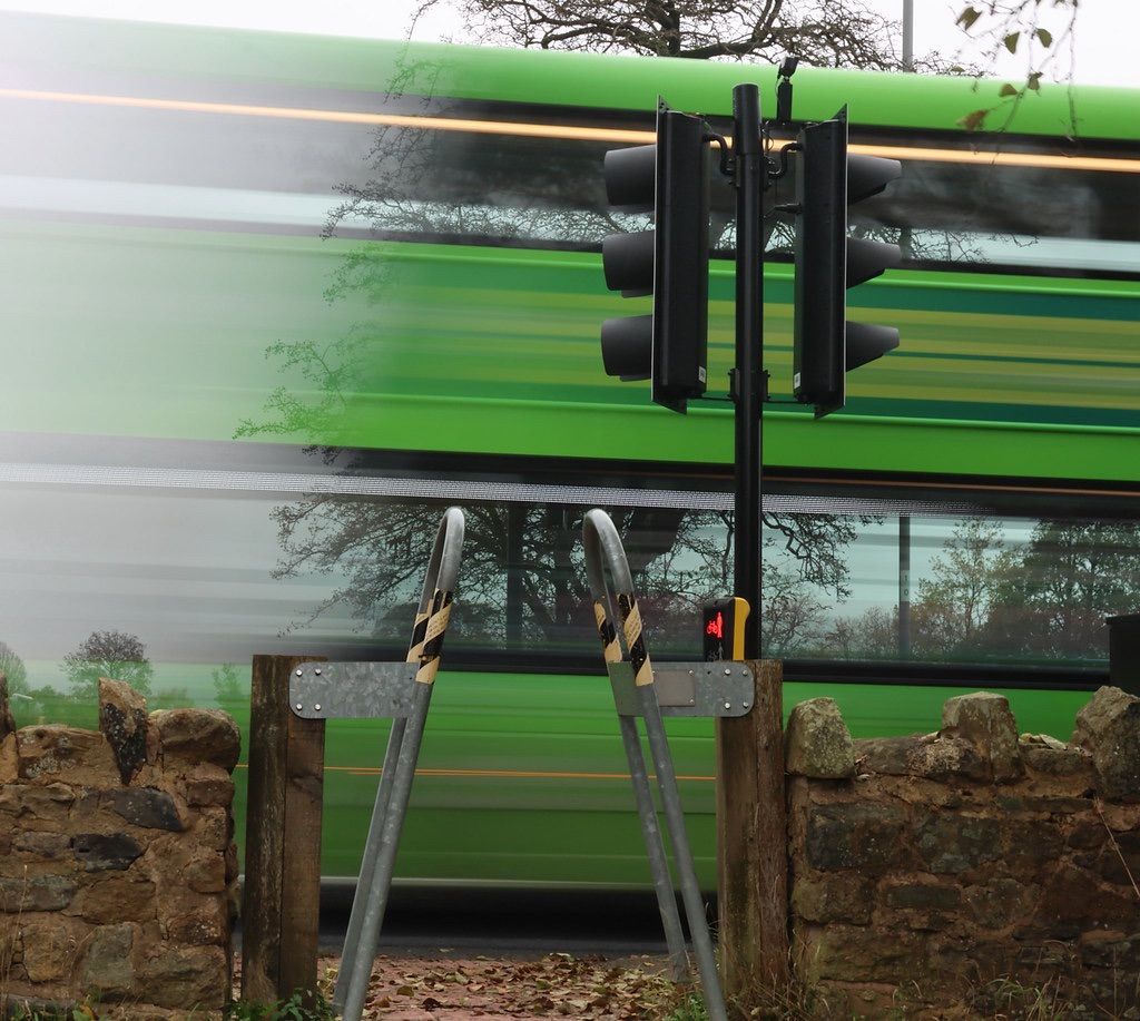 green blur of a bus passing a brick wall