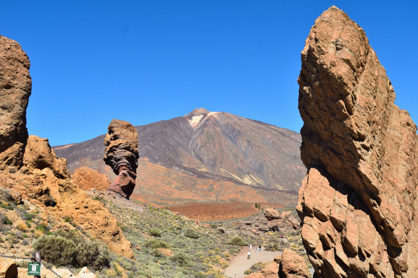 orange stones in front of a huge mountain. blue sky in the sun. 